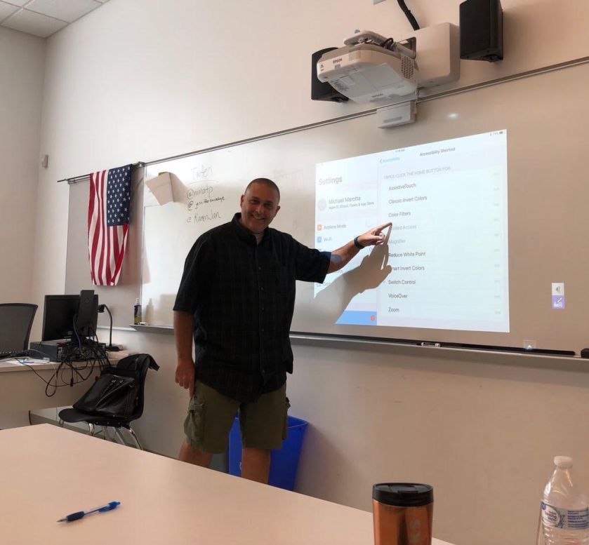 Mike pointing at projection on whiteboard showing iPad Accessibility features